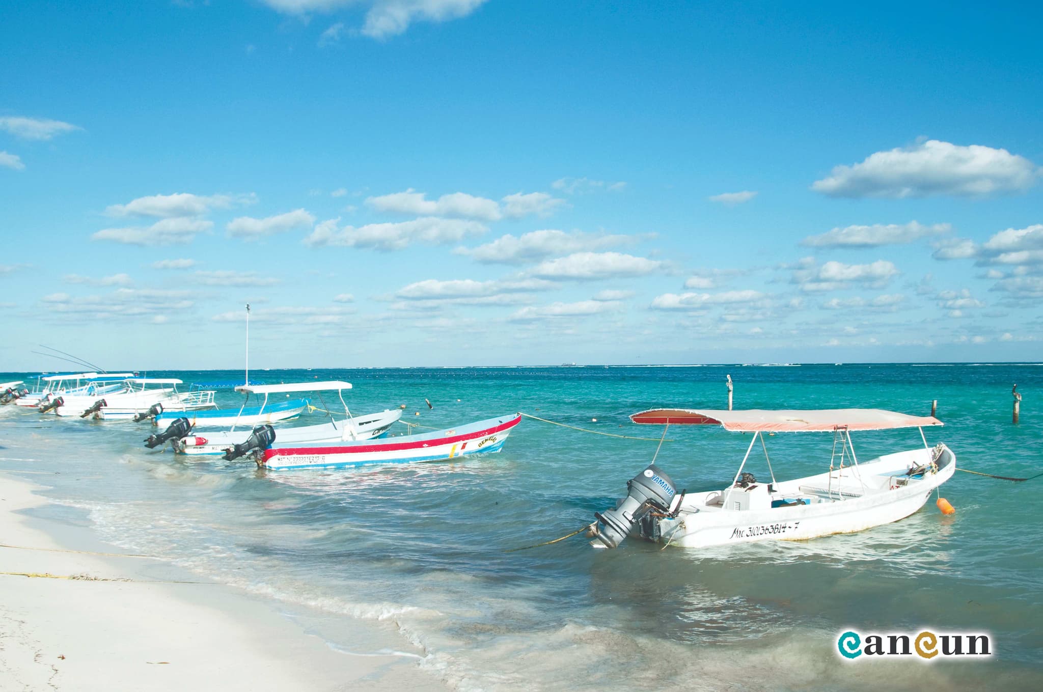 Playa de Puerto Morelos con lanchas de pescadores y el faro inclinado